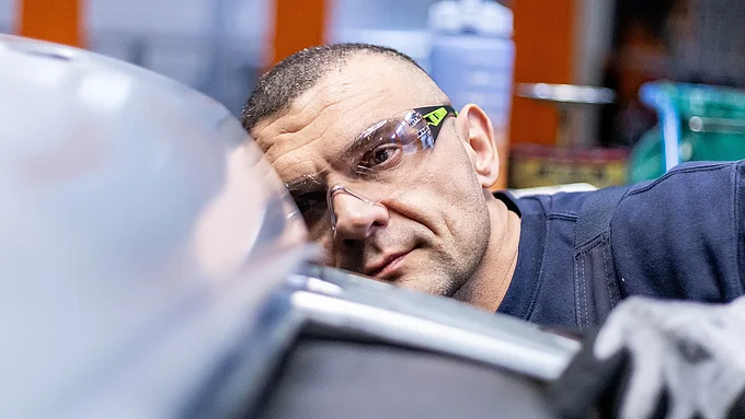 Mitarbeiter schaut sich ein Original Ersatzteil in der Fertigung an
